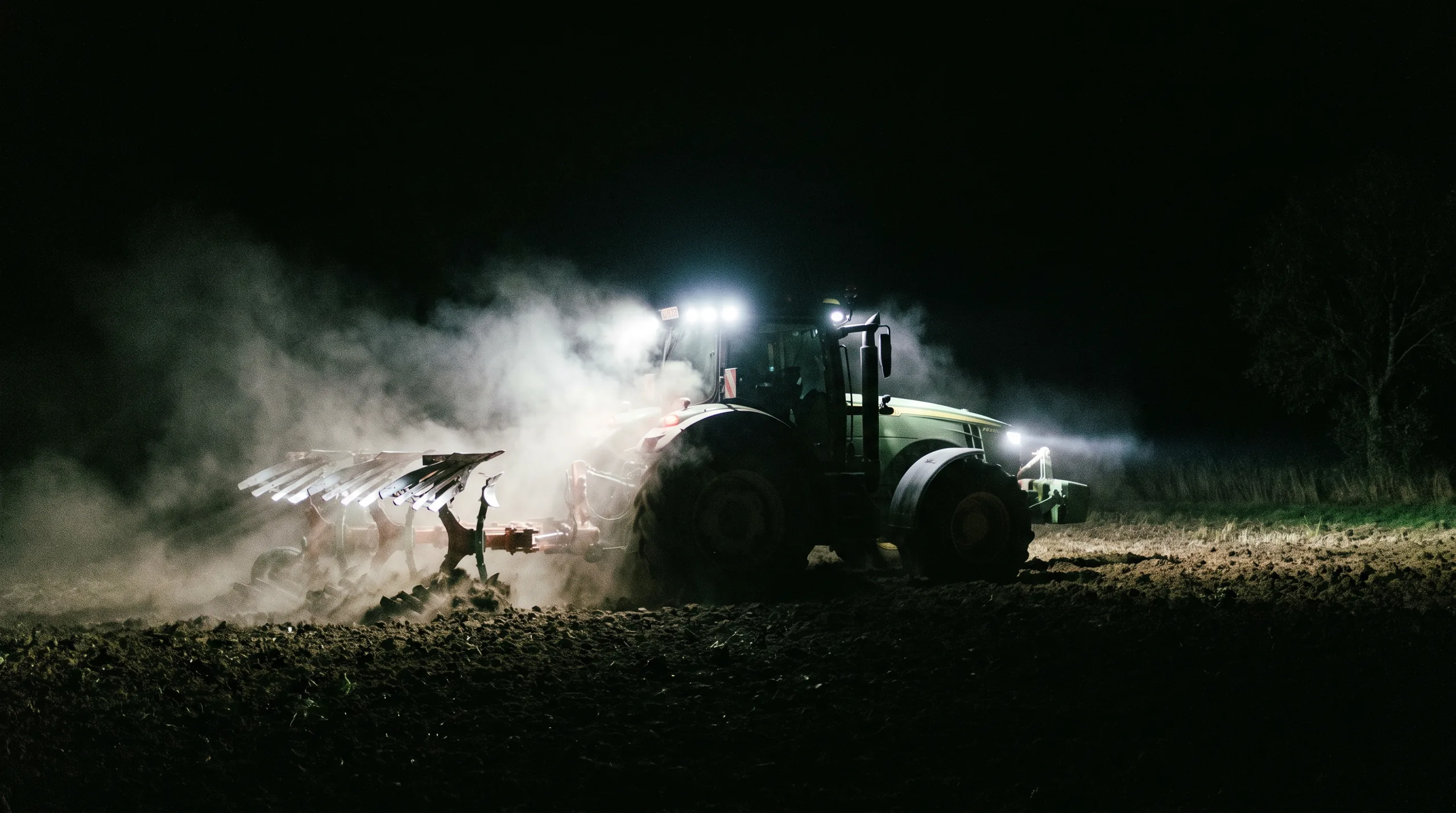 A tractor working a field at night under LED work lights